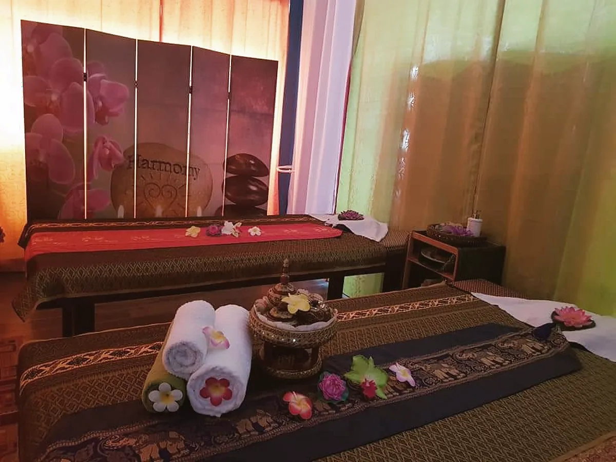 Raum mit zwei Thai-Liegen, Orchideen-Paravent und gerollten Handtüchern